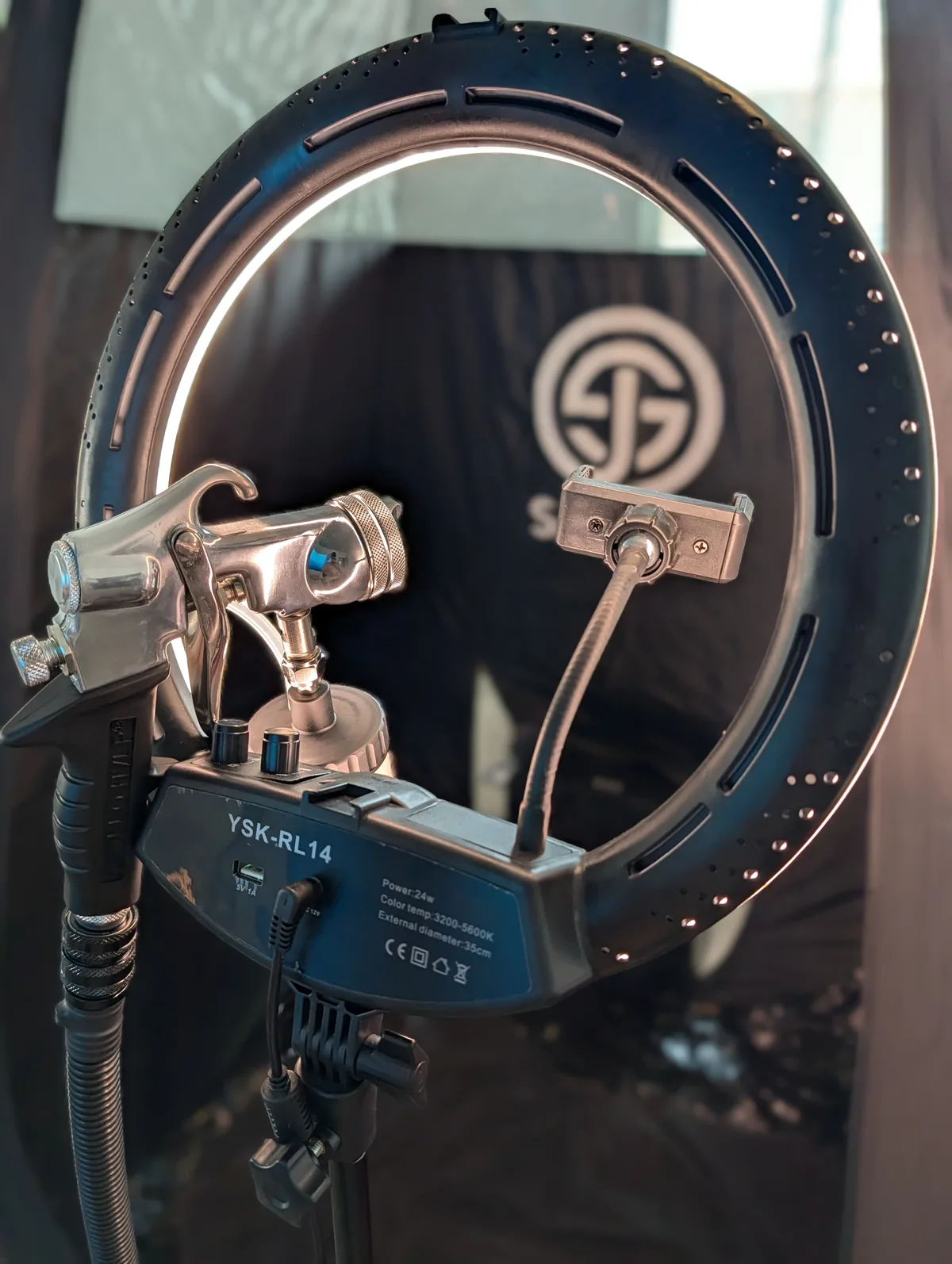The Glowtoure professional mobile spray tan setup — ring light and airbrush gun against the branded Glowtoure backdrop