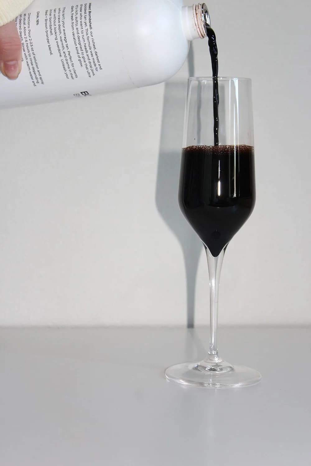 Custom spray tan solution being poured to mix a bespoke color and contour depth